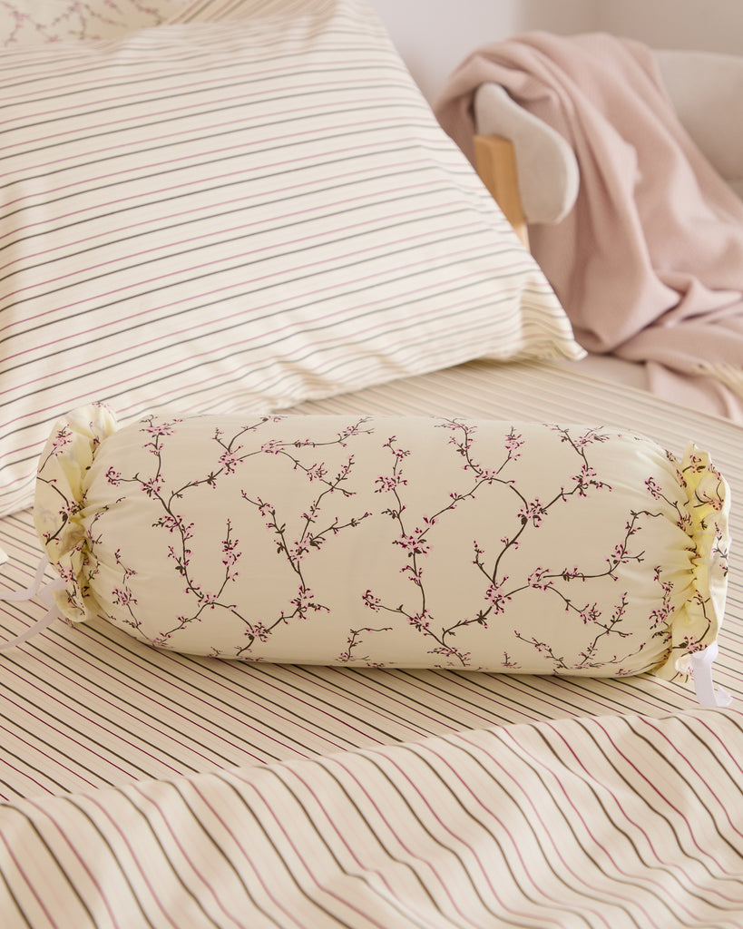 Foxford Tess Bolster with wildflower design, styled on cream duvet set with pink, brown and green stripes – Irish designed bedroom accessory