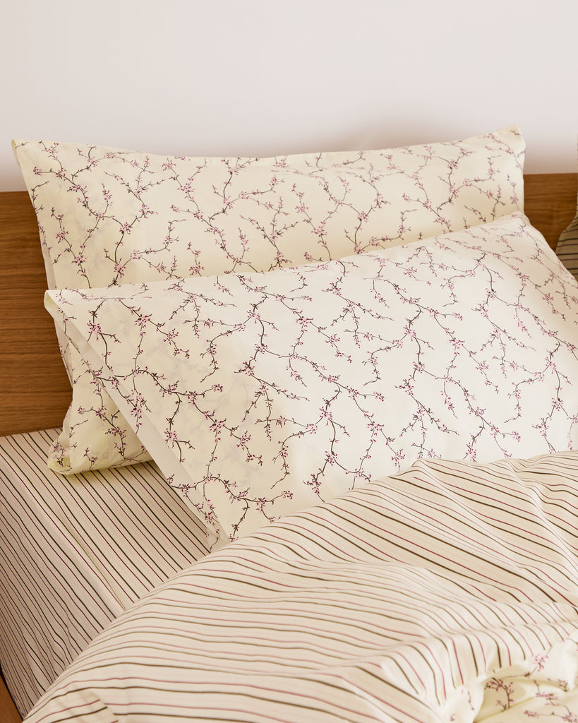 Floral patterned pillowcases on a bed with a wooden headboard.