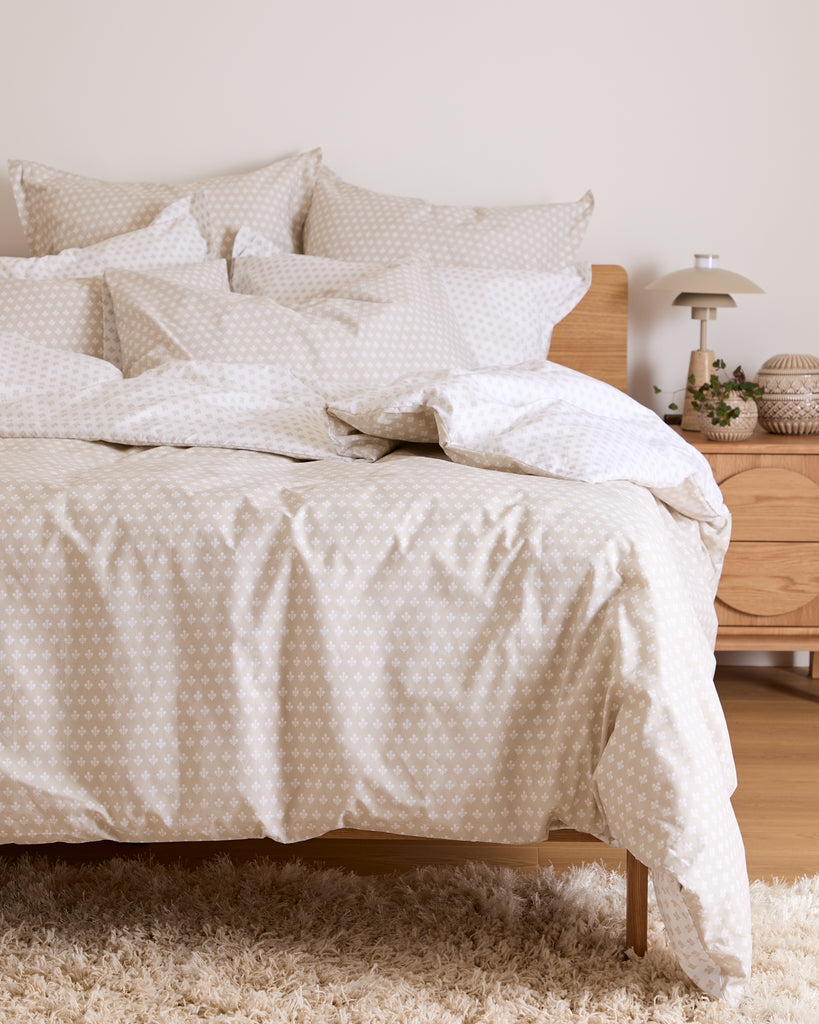 Neatly made bed with floral bedding in a bedroom setting.