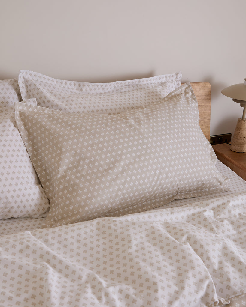 Neatly made bed with patterned bedding and pillows in a bedroom setting.