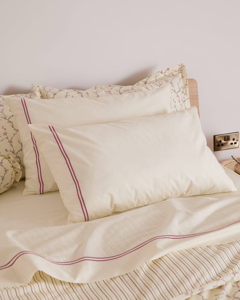 Neatly made bed with cream pillows and matching bedding.