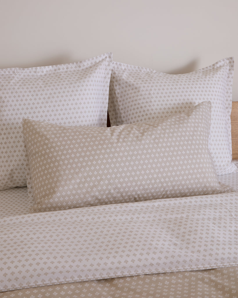 Patterned pillows and bedspread on a bed against a neutral wall.