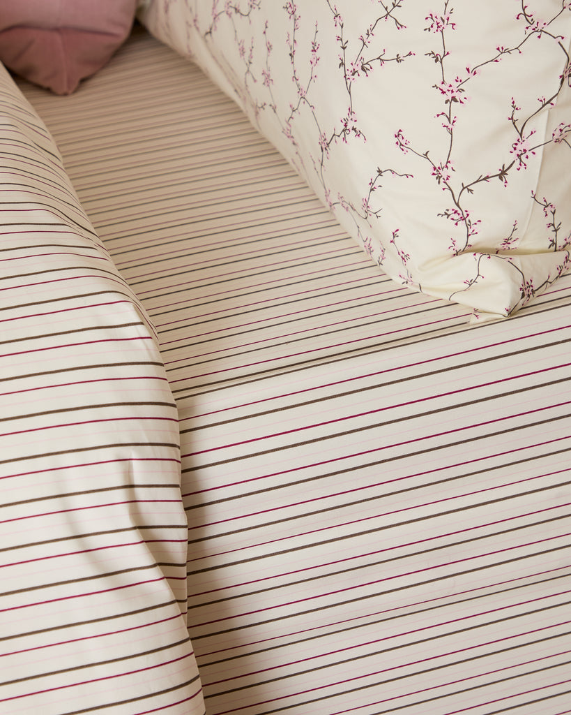Close-up of striped bedding with a floral-patterned pillow