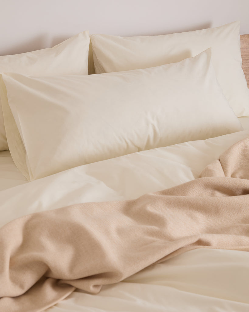 cream king bedding set with pillows on a bed