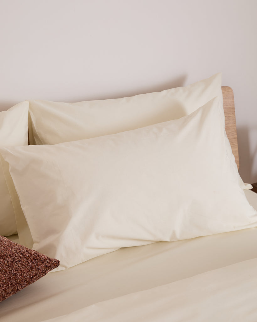 cream pillow on a bed with a neutral background